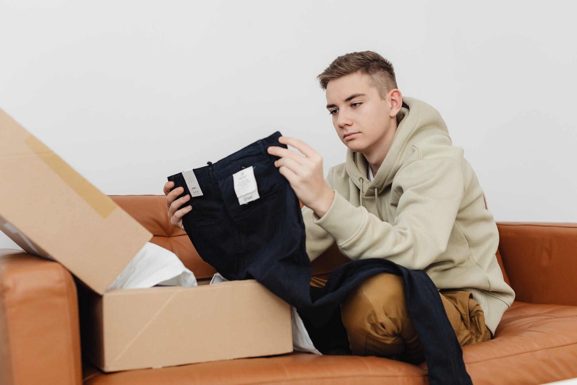 man wearing hoodie holding brand new pants