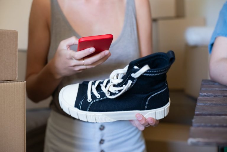 a person holding a shoe and a smartphone